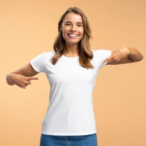 Smiling woman pointing down at her blank white t-shirt.